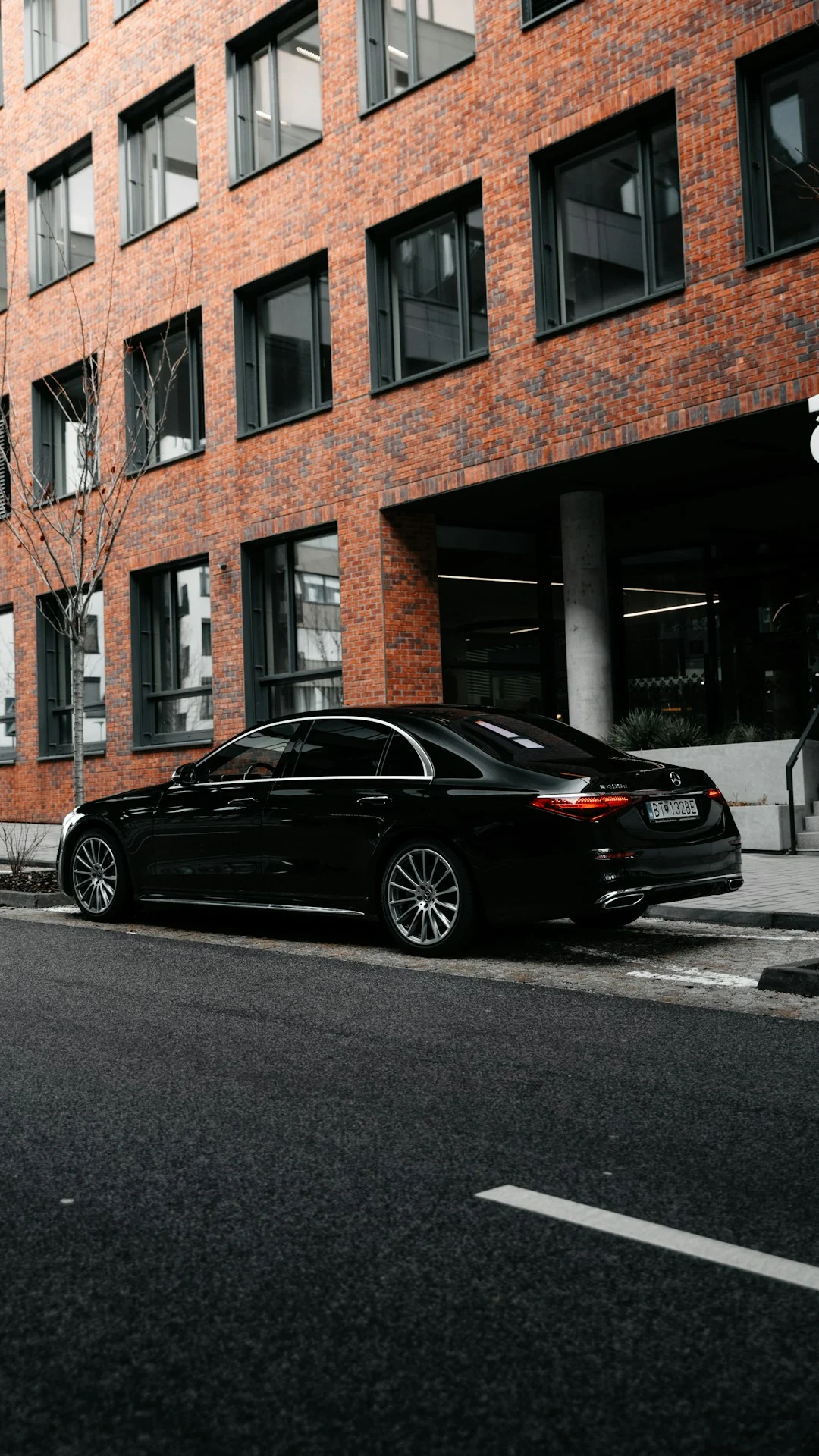 Berline Mercedes-Benz noire devant un immeuble contemporain
